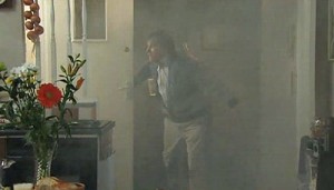 Roy fanning door in smoke-filled apartment